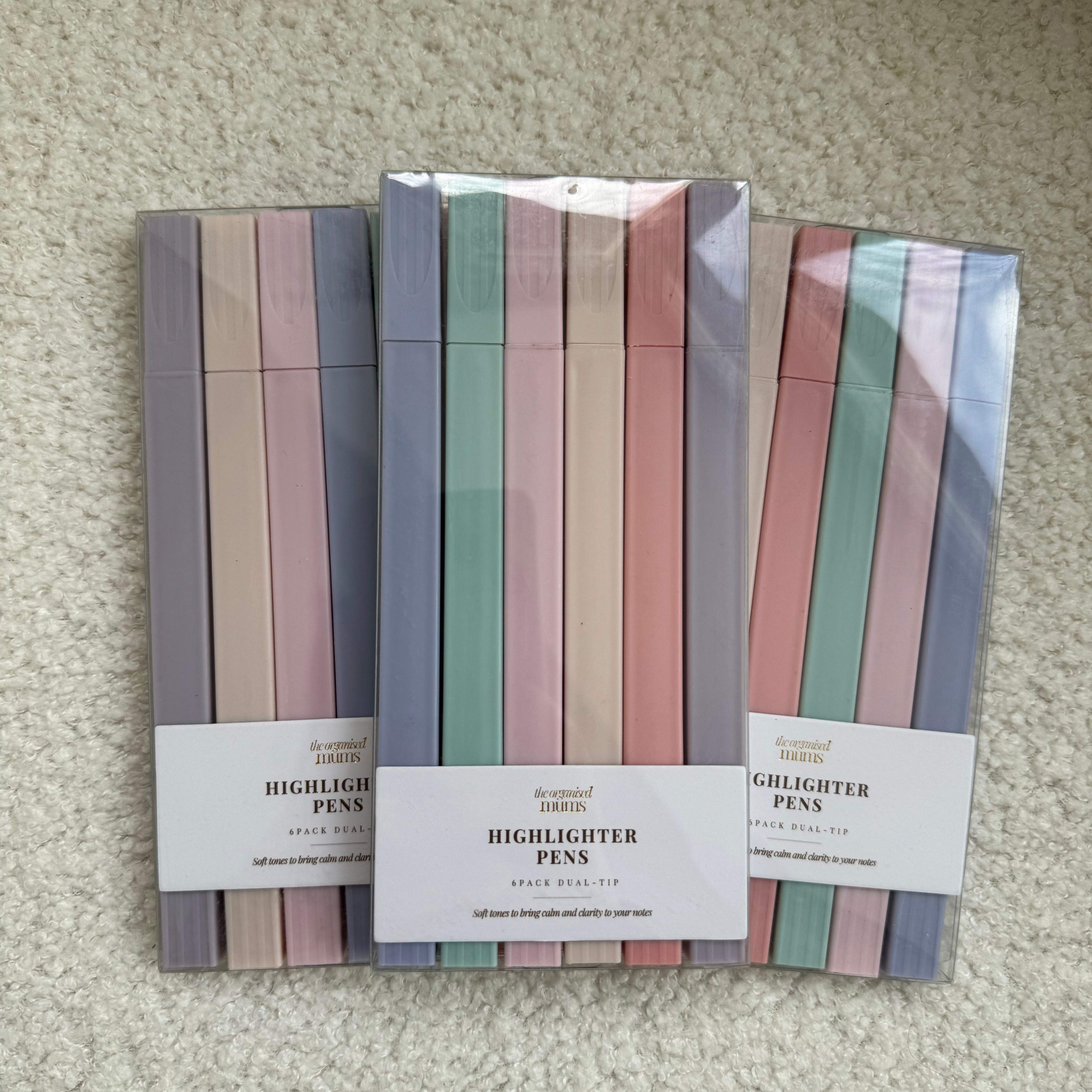 Stack of colorful highlighter packs with visible brand labels on a textured surface