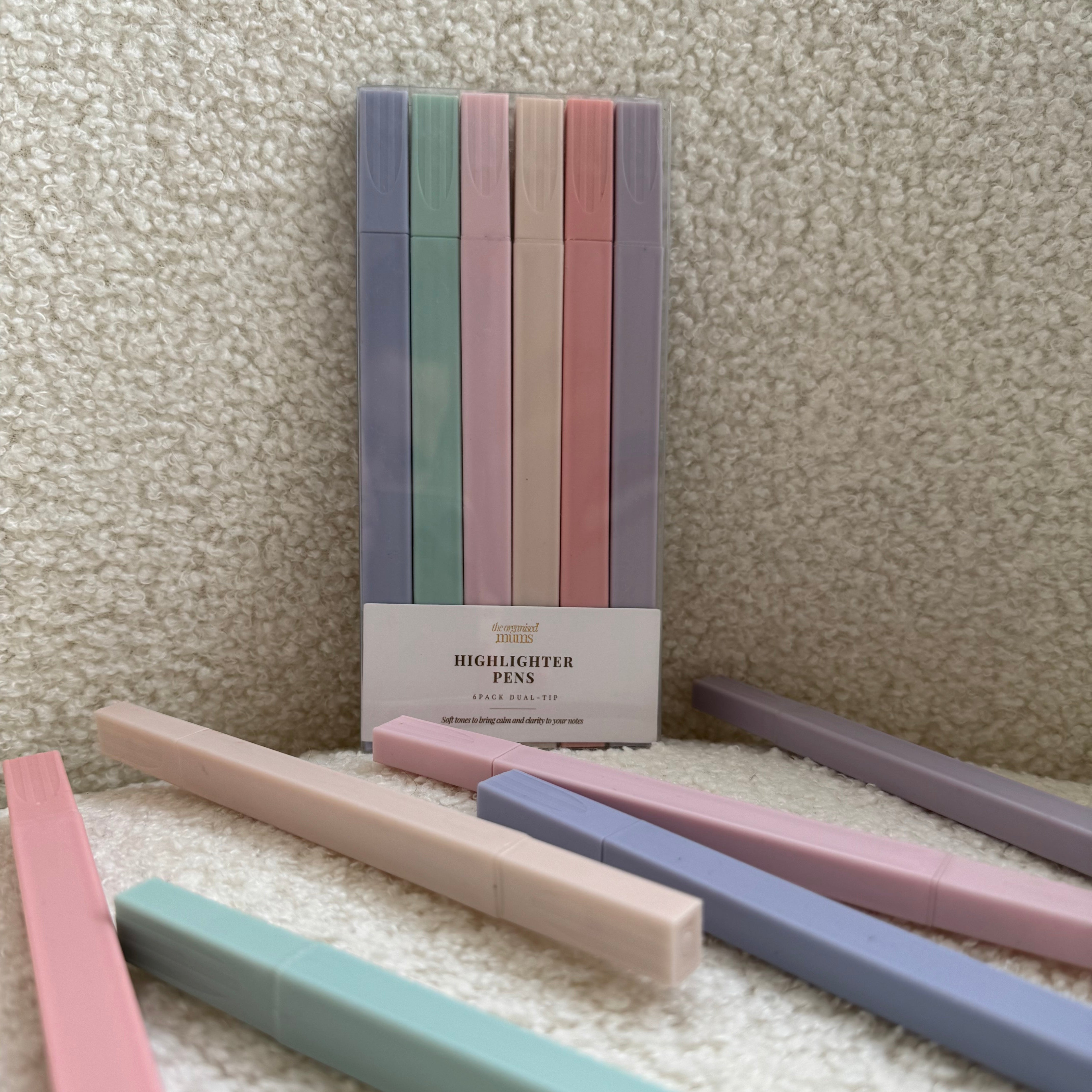 Set of pastel-colored pens on a textured surface